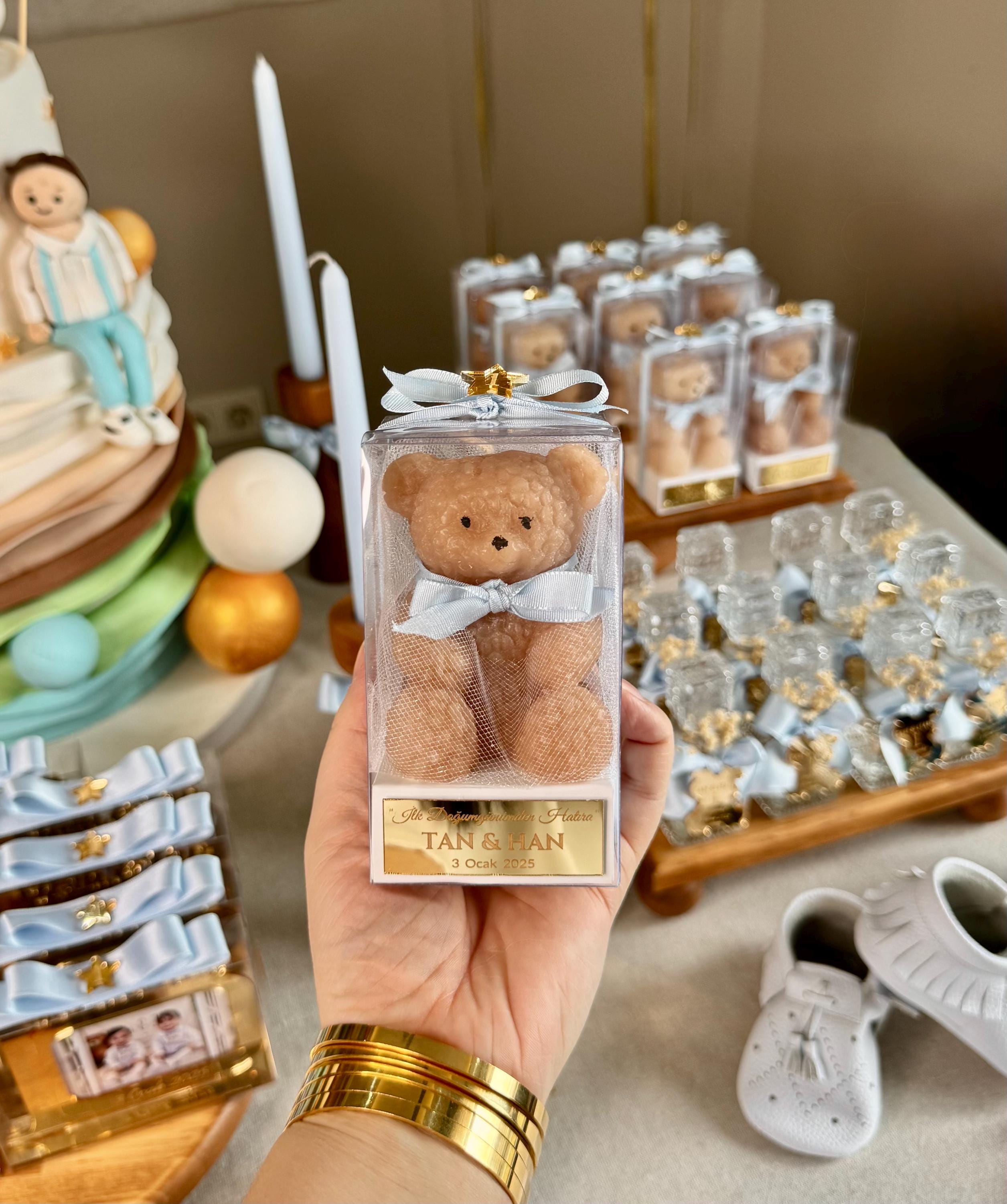 May include: A clear box with a brown teddy bear inside. The bear is wearing a blue ribbon. The box has a white label with gold text that reads &#39;It&#39;s a Boy!  Tan & Han 3 Ocak 2023&#39;